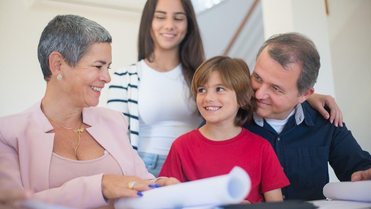 Smiling family indoors signing real estate documents. Friendly interaction and teamwork.